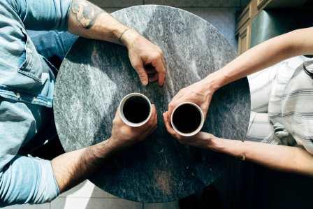 People sitting across the table from one another with cups of coffee