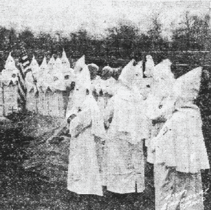 A grainy black and white image of a group of KKK members in hoods.
