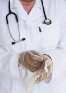 Health care worker removing latex gloves