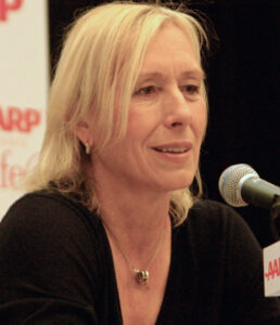 Martina Navratilova speaking into a microphone at an AARP event.