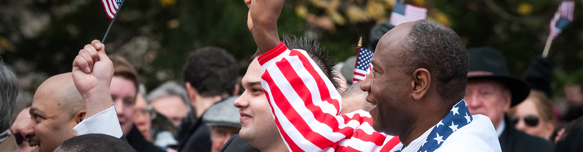 Newly naturalized immigrant citizens waving American flags at their Naturalization Oath Ceremony.