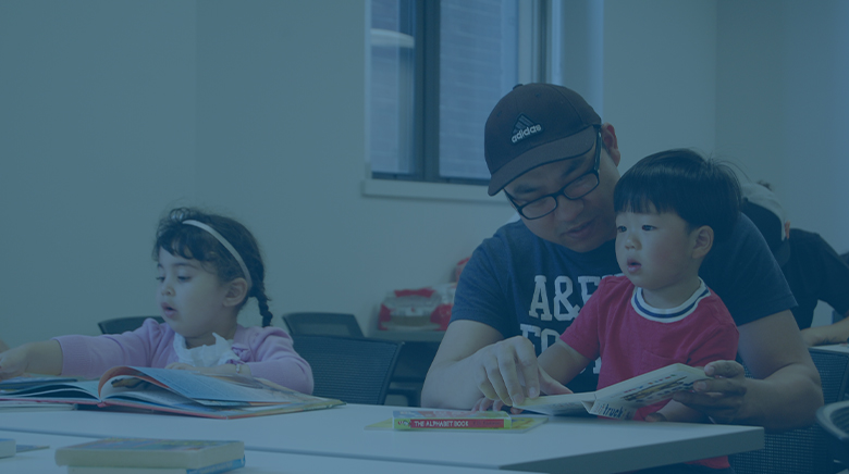 An immigrant father holding his son in a classroom.