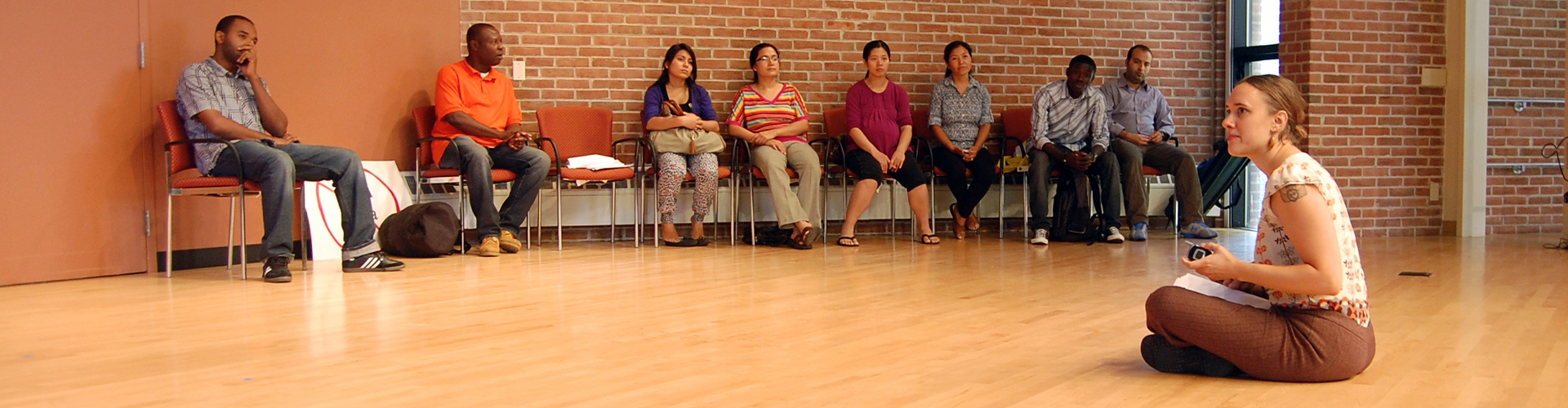 A group of immigrants sitting in a circle looking thoughtful.