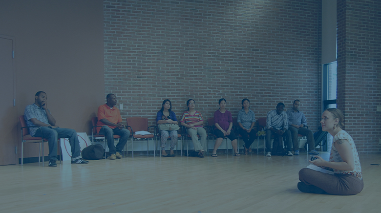 A group of immigrants sitting in a circle looking thoughtful.