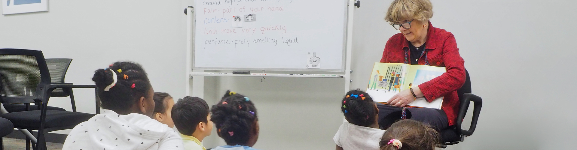 A teacher reading a book to elementary school-age refugee, unaccompanied minor and SLIFE students.