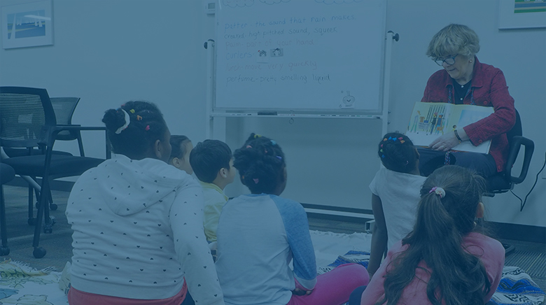 A teacher reading a book to elementary school-age refugee, unaccompanied minor and SLIFE students.