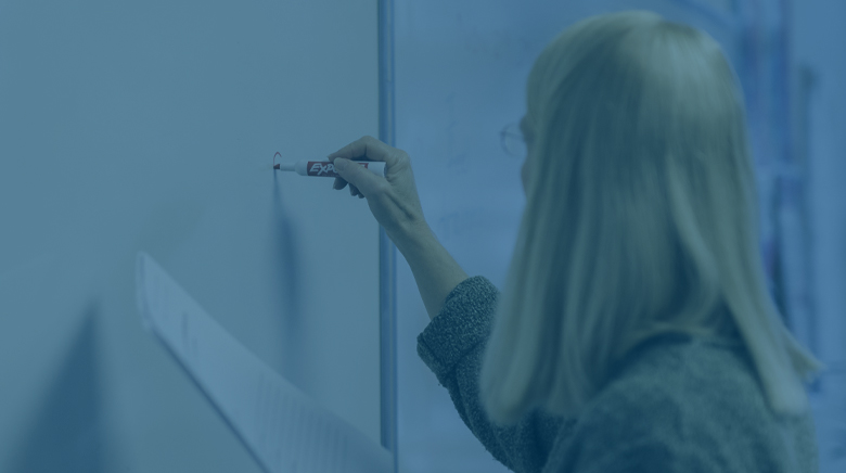 ESL teacher writing on classroom whiteboard using immigration lesson plans and resources