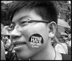 Protester with a sticker reading "Criminalizing hate, not HIV"