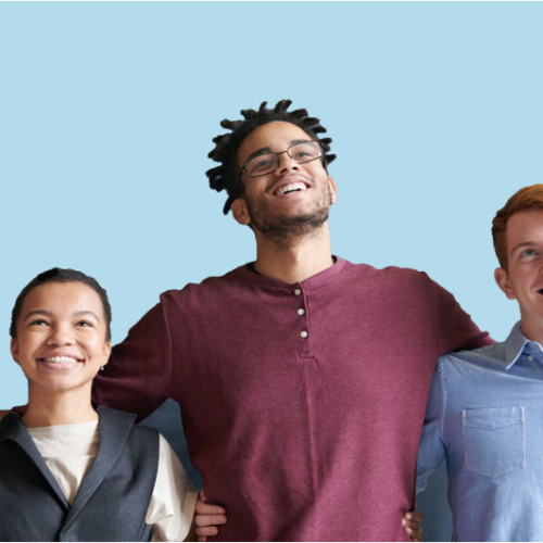 Three young adults, two men and a woman, in front of a blue background and smiling at something in the distance. The guy in the middle has his arms around the other two.