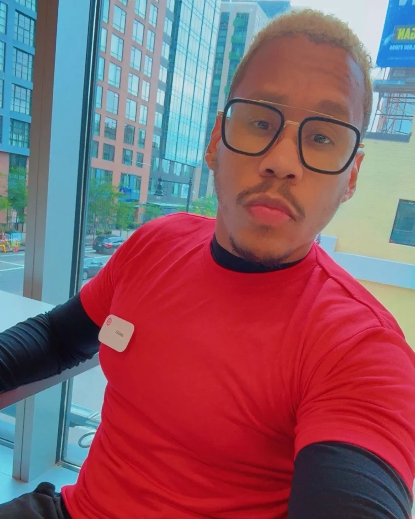 A man with bleached blonde hair and glasses in a red shirt with a Target nametag.